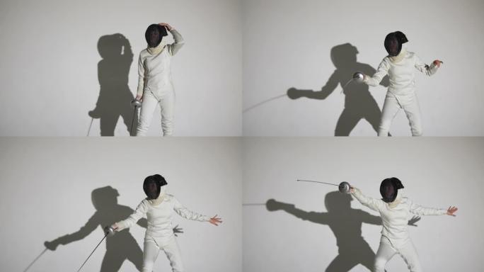 一名年轻女子击剑手的肖像用剑杆敬礼，戴上头盔，投掷攻击性打击。运动员在带有阴影的白色背景上的黑暗工作
