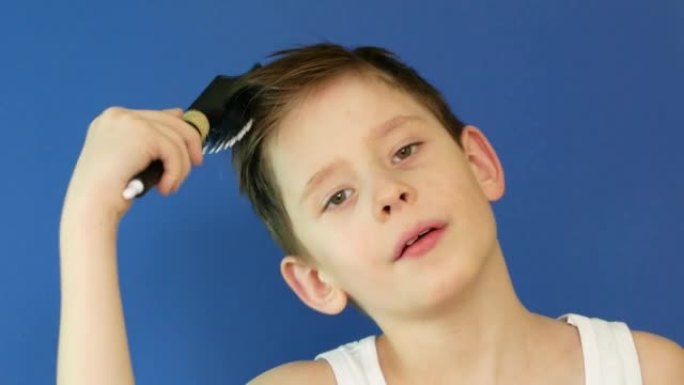 肖像高加索男孩8岁的早晨在镜子前梳头，唱歌并举起梳子。普通人的日常生活。一个男生梳头，上学