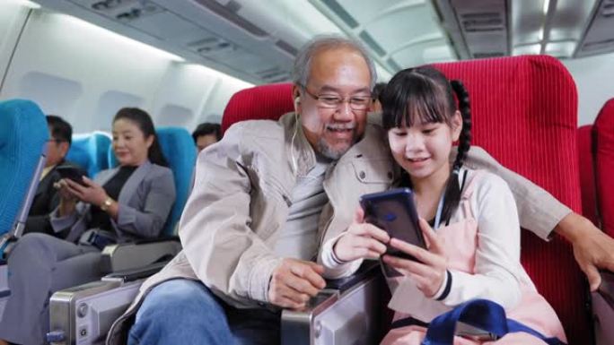 亚洲老祖父和他的侄女喜欢在船上旅行时一起在智能手机上看电影，共享耳机