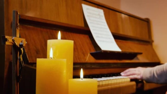 用燃烧的蜡烛和耶稣受难像在立式钢琴上演奏宗教基督教音乐