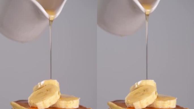 香蕉煎饼倒枫糖浆。慢动作，垂直镜头