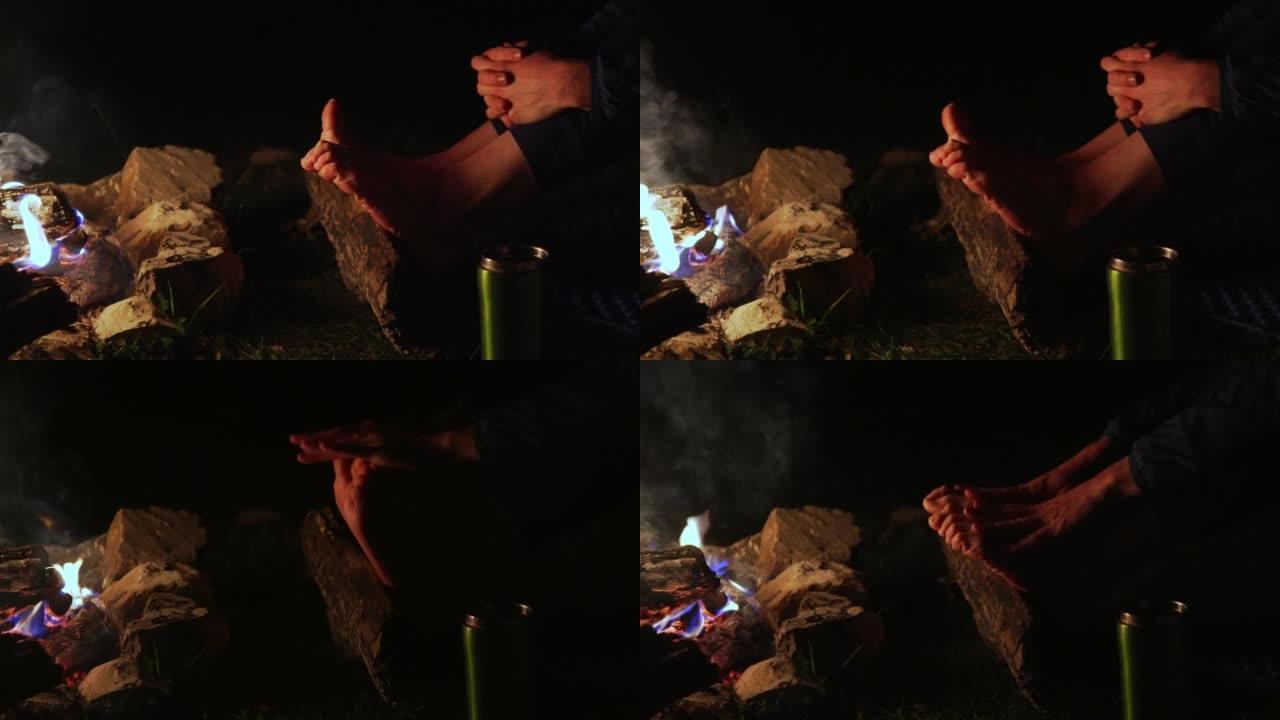 女性在夜晚的篝火旁晒脚并跳舞手指