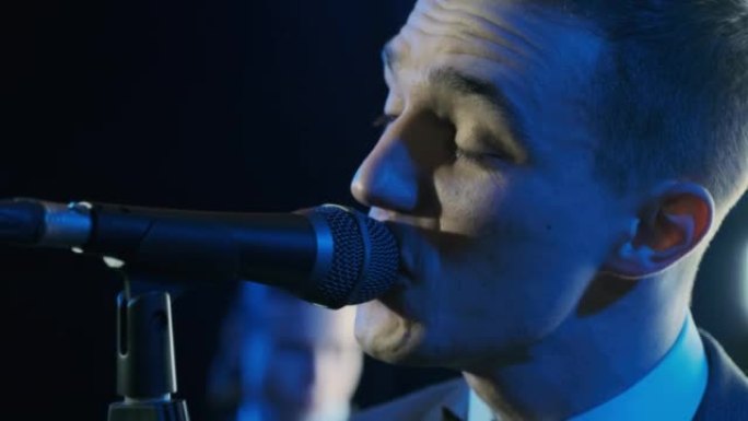 男子在摇滚音乐会舞台上表演时用麦克风唱歌。Close up man rock star歌手在五颜六色