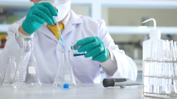 亚洲男性医学科学家研究人员穿着实验室外套和防护设备，在寻找潜在的新型冠状病毒肺炎疫苗时，仔细检查，测