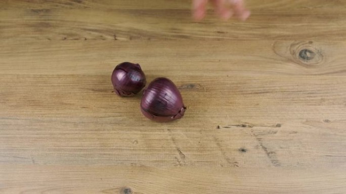 男人把紫色洋葱放在木制桌子上。新鲜全洋葱