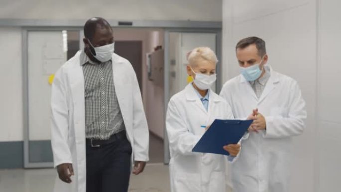 穿着实验室外套和防护口罩的医生团队讨论患者医学测试
