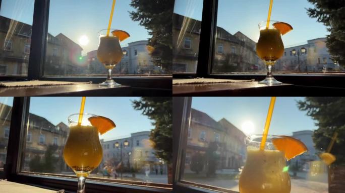 猕猴桃汁和橙子饮料在窗户和明亮的阳光下的背景下，玻璃玻璃上有一块橙子