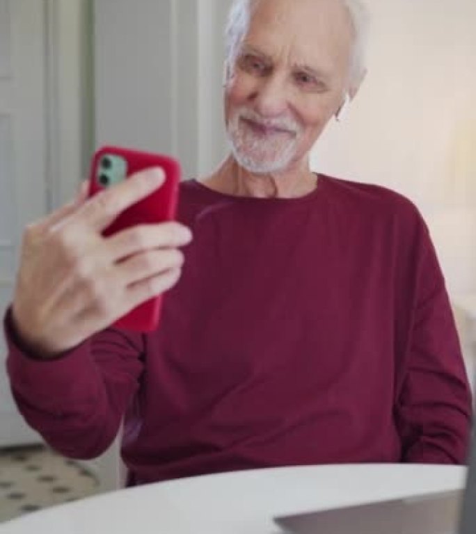 爷爷在智能手机上拍摄有趣的自拍照，并查看生成的照片