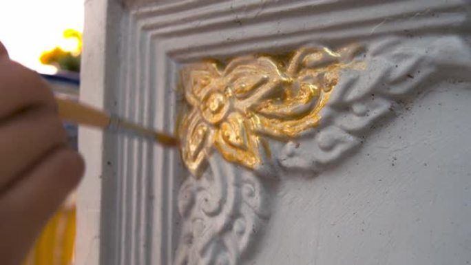 画家正在旧神社的元素上画金色。