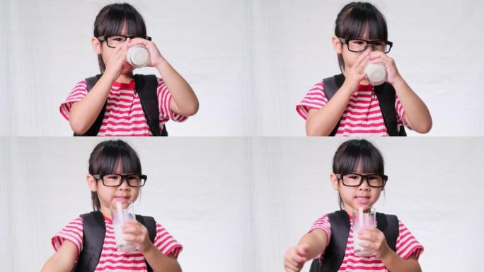 可爱的女学生上学前喝玻璃杯里的牛奶。儿童健康营养。回到学校的概念