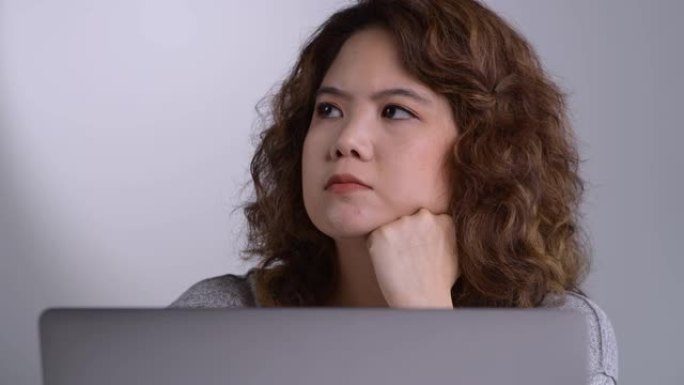 感到疲倦和压力。年轻的亚洲妇女坐在办公室里用笔记本电脑工作时，思想深处疲惫不堪。