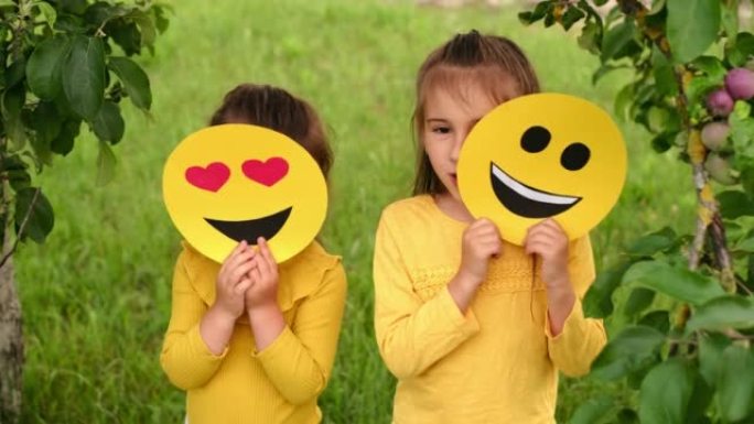 孩子们躲在快乐表情符号的纸板照片后面。世界微笑表情符号日。