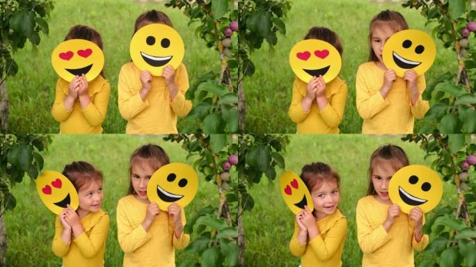孩子们躲在快乐表情符号的纸板照片后面。世界微笑表情符号日。