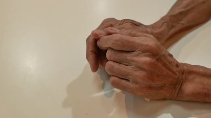 一个老人皱巴巴的老疲惫的手的特写。这个人擦着手，抚摸着手臂上的骨头。养老金领取者的手
