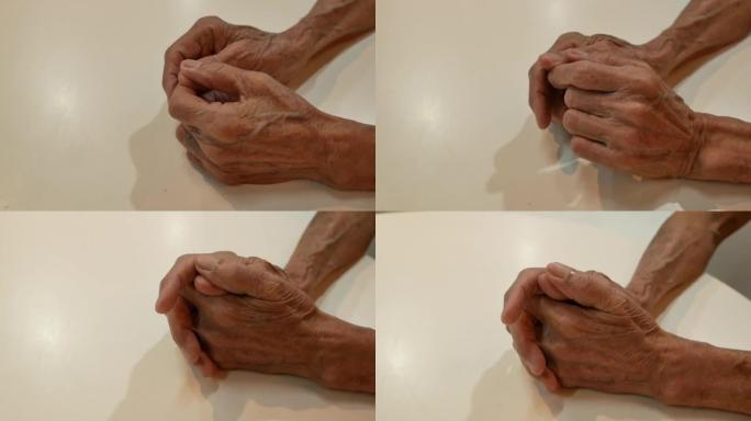 一个老人皱巴巴的老疲惫的手的特写。这个人擦着手，抚摸着手臂上的骨头。养老金领取者的手