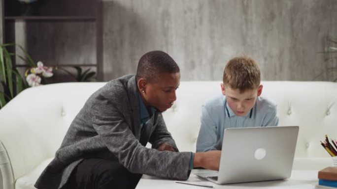 黑人老师向男孩解释笔记本电脑上的教育材料
