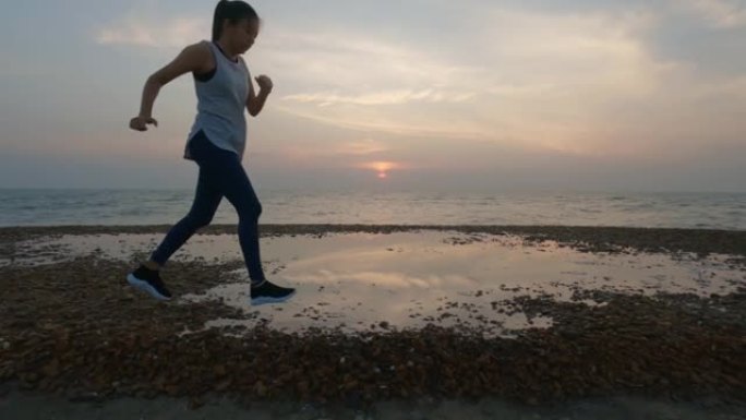 亚洲妇女在早晨日出背景下在海边跑步之前进行热身运动。