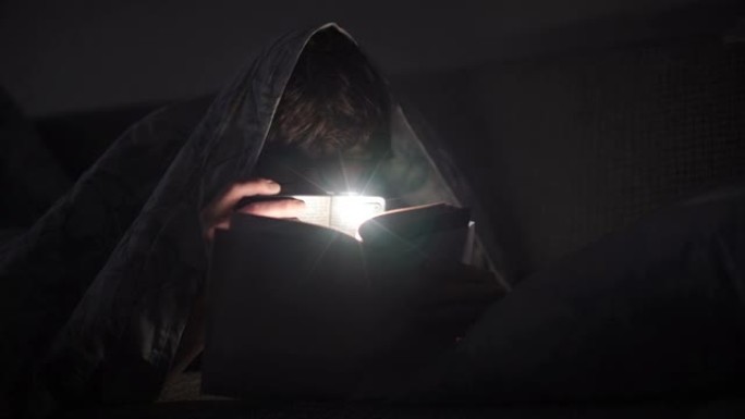男人晚上用手电筒看书。