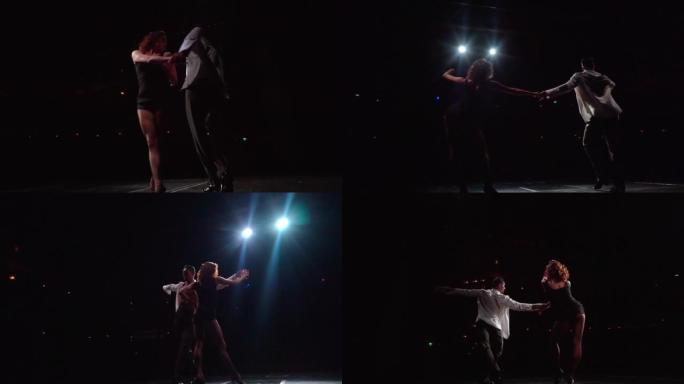 在泛光灯光的舞台上，一群交谊舞舞者在黑暗中表演着拉丁美洲的古典舞步，摆动着臀部和手臂，镜头从下面掠过