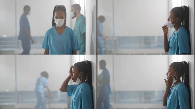 精疲力竭的非洲护士靠在医院走廊墙上，取下安全口罩