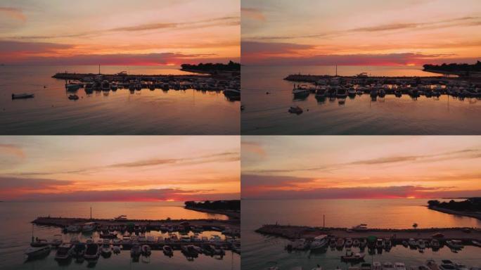 夏天在克罗地亚亚得里亚海地中海的海滨海湾港口日落，假日度假旅游船和渔船在码头上。空中无人机空中飞行从