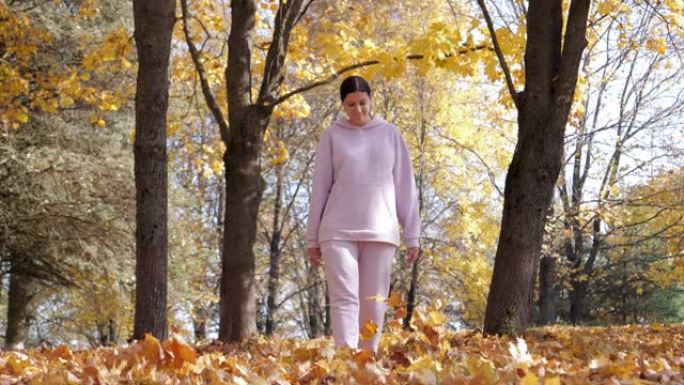 女人走在秋天森林中倒下的枫叶的地毯上