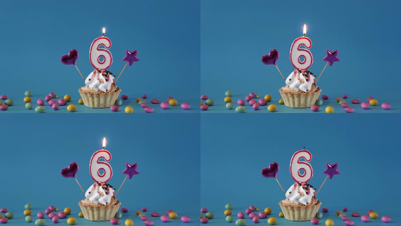 祝6岁的孩子生日快乐，带蜡烛的生日蛋糕和蓝色背景上的生日装饰品。点燃并熄灭纸杯蛋糕上的节日蜡烛