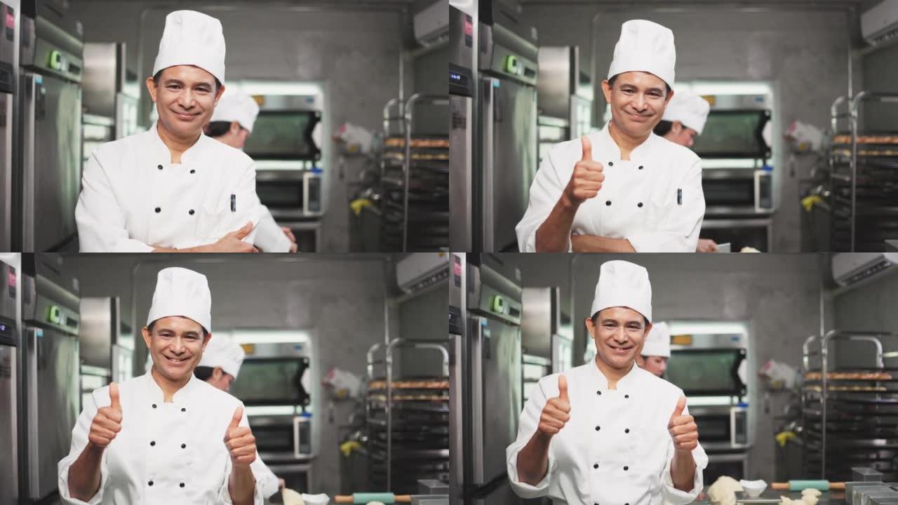 高级厨师面包师看着相机。厨师面包师穿着厨师的衣服和帽子，在厨房里一起做饭。年轻的亚洲人从厨房的现代电