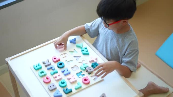 亚洲男孩学习英语字母，玩具和字母。返校的概念