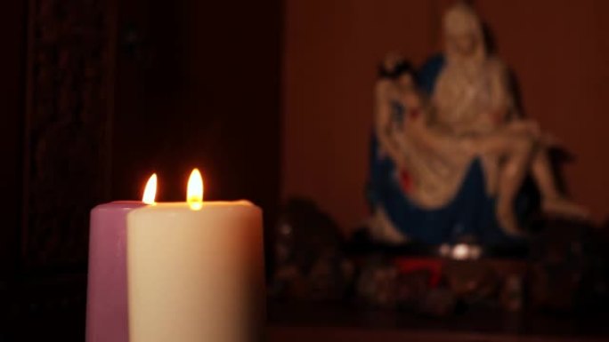2017年3月13日，雅加达: 两支燃烧的蜡烛的视频片段，背景上有一个Pieta雕像