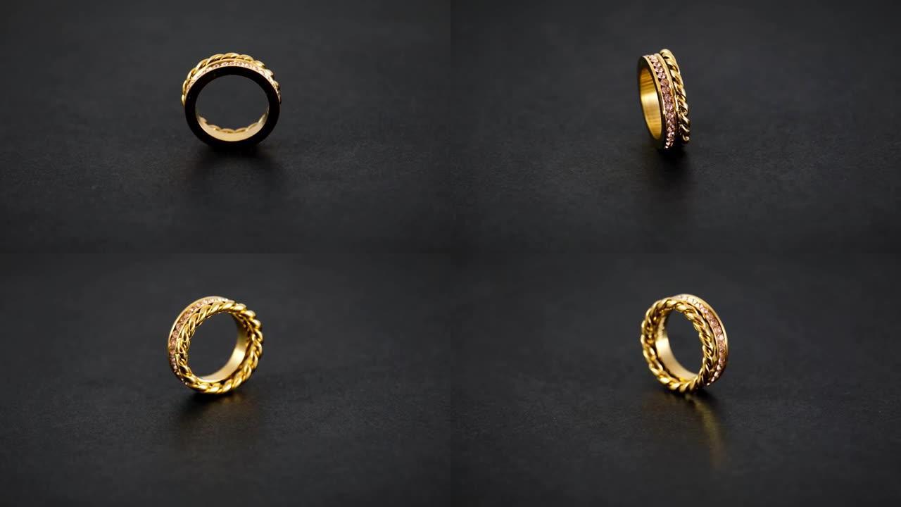 旋转金色打结闪闪发光的双金戒指，黑色背景上有锆石。美丽的情人节礼物。