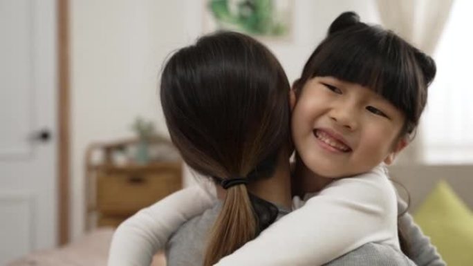 慢动作，选择性地聚焦快乐的亚洲女孩在母亲节在家的客厅用笑脸拥抱妈妈