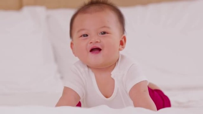 新生儿躺在胃部发育的颈部控制。增强婴儿颈部和肩部肌肉的肚子时间。可爱的婴儿躺在白色床上爬行快乐和乐趣