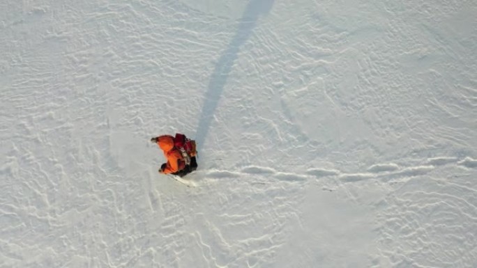 4k镜头-一个背着背包的孤独旅行者走过白雪皑皑的沙漠。在极冷条件下生存的概念