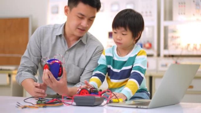 亚洲学生和老师使用电子仪表和笔记本电脑在科学课中构建自主自驱动机器人汽车的原型