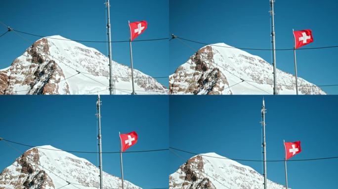 风吹瑞士阿尔卑斯山顶部蓝天背景上的瑞士国旗。