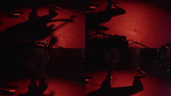 从红色灯笼舞台上演奏的摇滚吉他手移动抽象阴影。重型摇滚乐队表演现场音乐会的黑暗大气场景