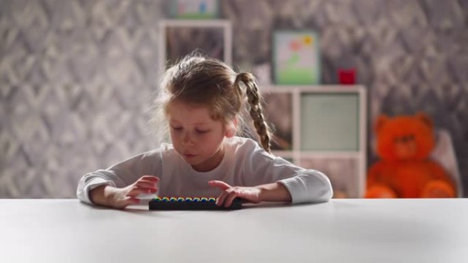 有玩具算盘的聪明小女孩坐在桌子旁做总和
