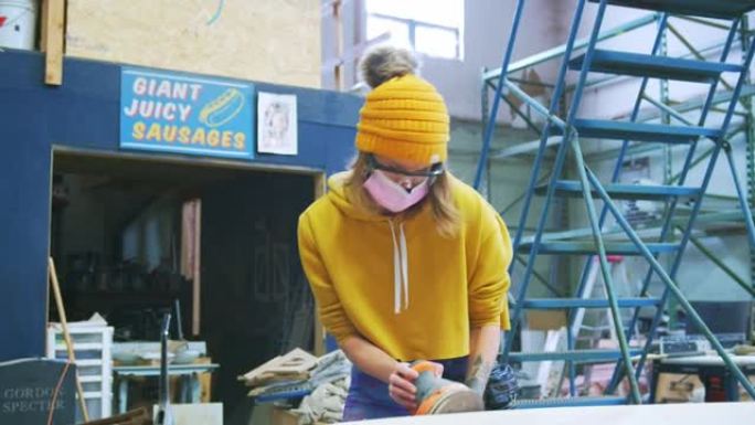 在木材商店使用电动工具的年轻女艺术家