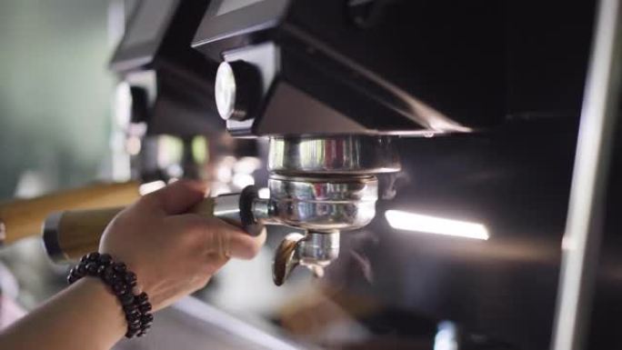 特写将过滤器支架连接到餐厅咖啡厅室内的浓缩咖啡机上。女性高加索人的手将研磨的咖啡豆粉附着在慢动作中准