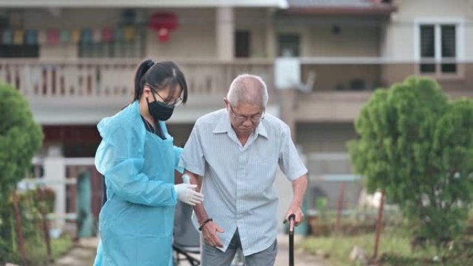 亚洲华裔女性理疗师用拐杖帮助老人在公园散步