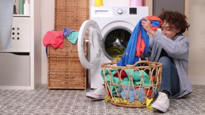 洗脏衣服。衣服闻起来很难闻。一个男孩闻着脏衣服，厌恶地把它们扔进洗衣机