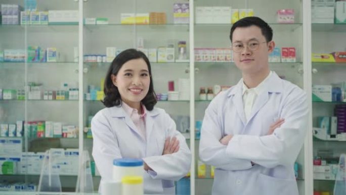两位亚洲女人和男药剂师带着可爱的友好微笑站在药房药店双臂交叉。医学、药剂学、保健和人的概念。