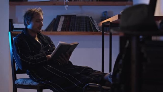 一个穿着睡袍的男人在台灯下在家看书。家庭教育和消遣。