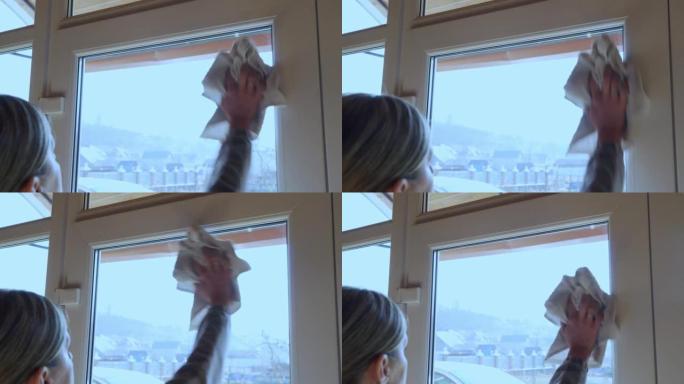 一个女人用抹布擦房子里的窗玻璃。