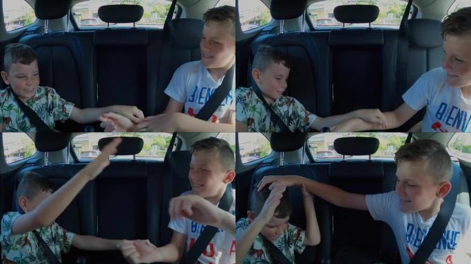 两个年轻的淘气男孩在汽车后座上互相抚摸和惹恼时打架和退缩。战斗升级，腿即将开始踢。