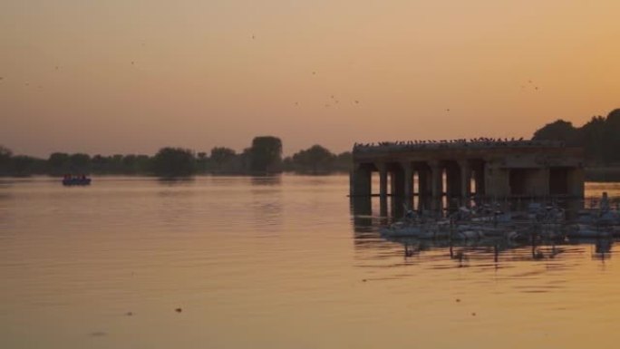日落期间，游客在印度拉贾斯坦邦的斋沙默尔湖的湖中划船，可以看到加迪萨尔湖。