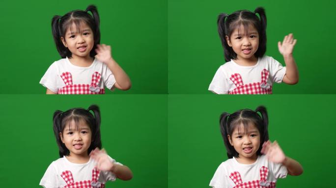快乐的亚洲儿童女孩的肖像运动到绿屏背景上的相机，一个孩子看着相机。学龄前儿童做梦充满能量感觉健康和良