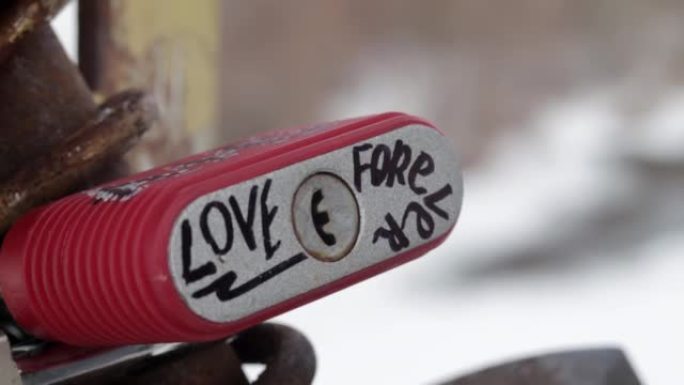 红色挂锁上永远爱的英文铭文。挂在桥上的锁着的爱情挂锁象征着牢不可破的爱情。手射
