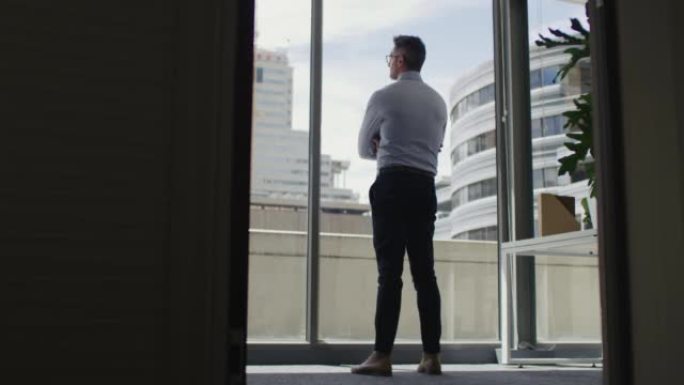 4k视频片段，一个成熟的商人在现代办公室里若有所思地看着窗外